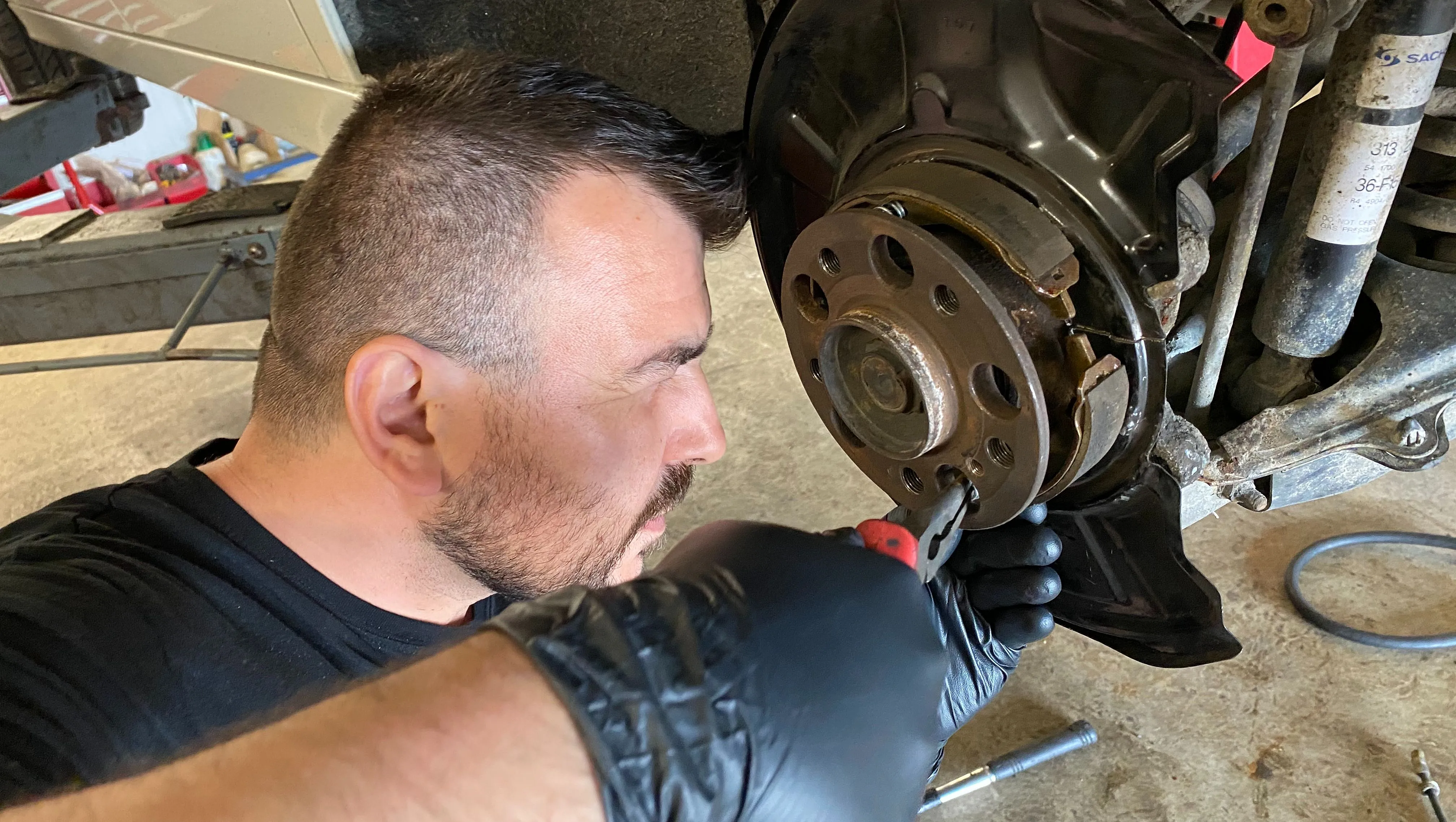 Bilmekaniker som gör bromsservice på en bil